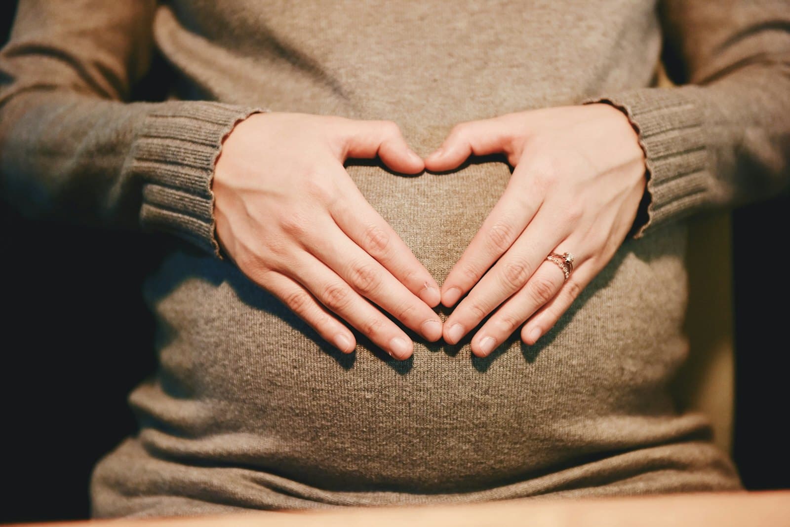 An expectant mother forming a heart shape with her hands