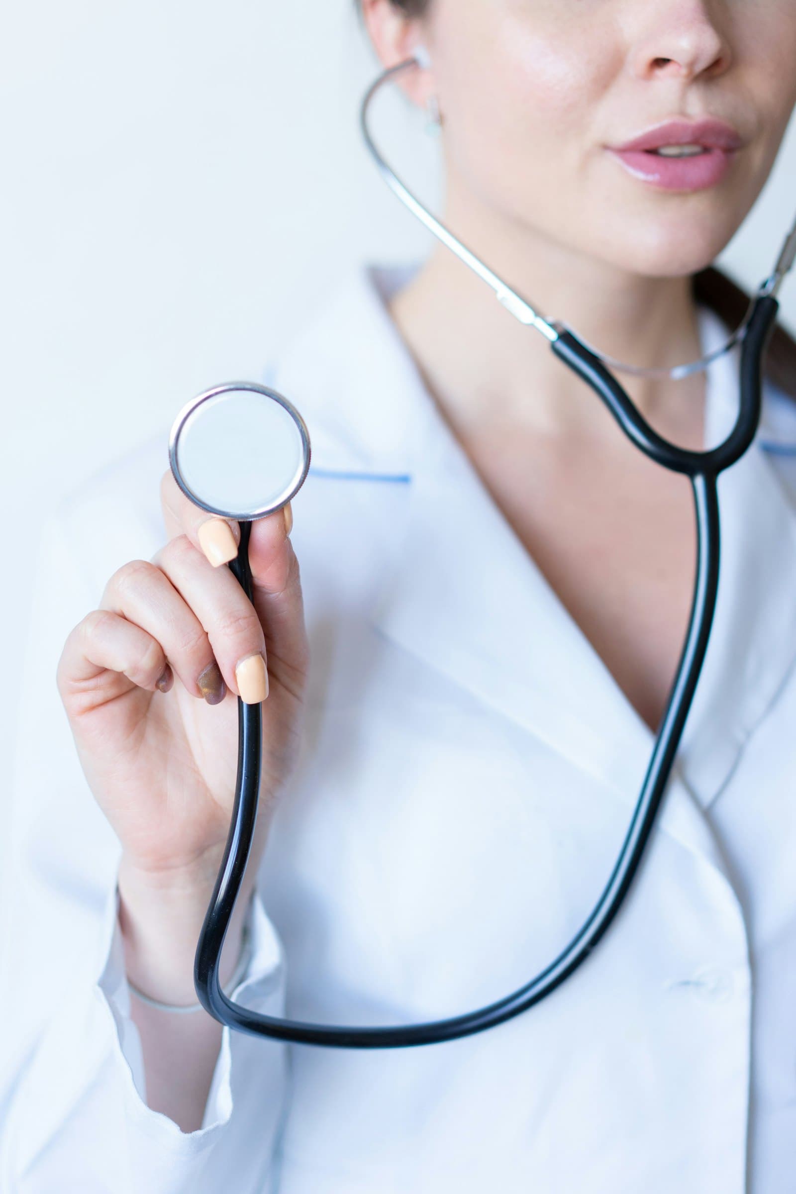 A female doctor in a white coat holding a stethoscope